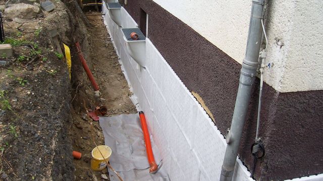 Einfamilienhaus mit Baugrube zur Kellertrockenlegung und Außenabdichtung als Symbolfoto für den Bereich Sanierung